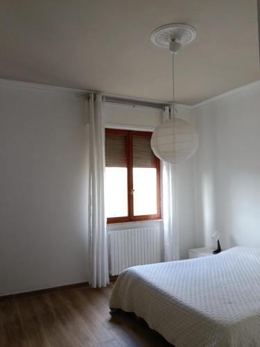 a white bedroom with a bed and a window at Casa Serena in Carrara