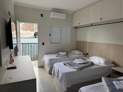 a hotel room with two beds and a television at Dallas hotel in Telêmaco Borba