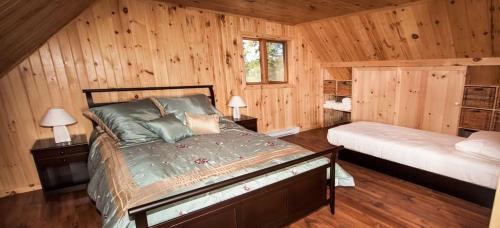 a bedroom with a bed in a wooden cabin at Les Chalets du Lac Serein (Ludger) in Saint Ludger de Milot