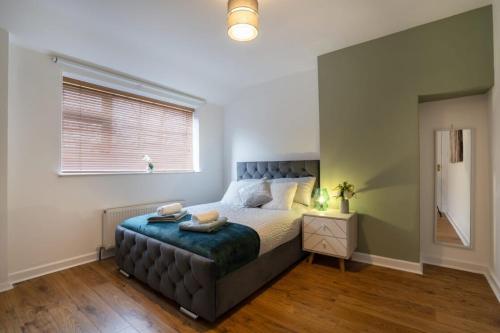 a bedroom with a large bed with a blue tufted foot board at 10-min to City Centre 2 Bedrooms Sleeps4 with Free Parking Garden & WiFi in Aberdeen