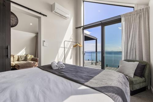 a bedroom with a bed with a view of the ocean at Roam Taupo Upper Terrace Unit 4 - Spa Pool in Taupo