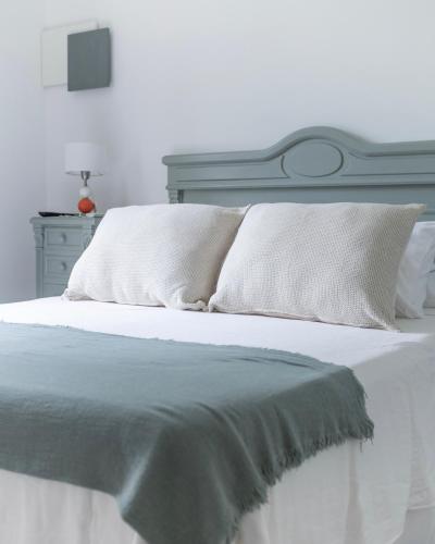 a white bed with white sheets and pillows on it at Los Narcisos in San Antonio de Areco