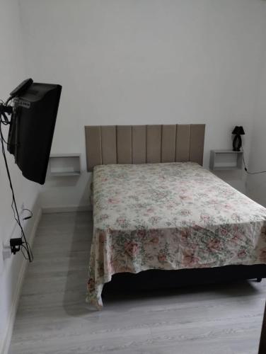 a bedroom with a bed with a flowered blanket and a television at Cantinho da Paz in Socorro