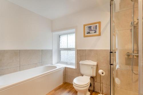 a bathroom with a toilet and a tub and a window at 4 Bed in Stokenham oc-i34021 in Stokenham