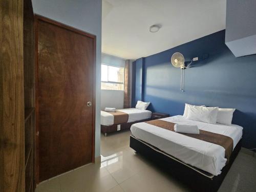 a bedroom with two beds and a blue wall at Barlovento Business Hotel in Piura