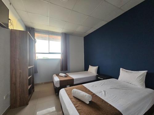 a bedroom with two beds and a blue wall at Barlovento Business Hotel in Piura