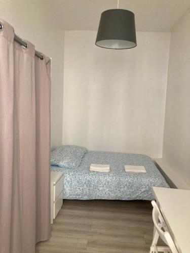a small bedroom with a bed and a lamp at Hôtel de Ville, T3, 2 chambres, 2 salles de bain in Saint-Étienne