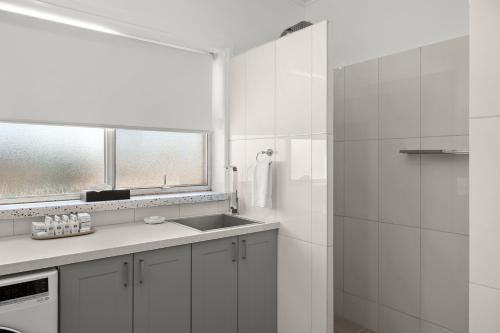 a white bathroom with a sink and a mirror at Loxton Courthouse Apartments in Loxton