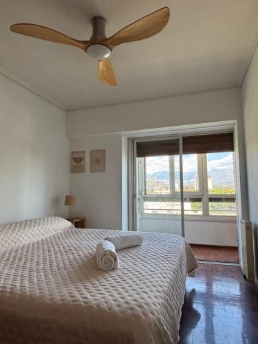 a bedroom with a bed with a ceiling fan and a window at La Plaza Apart in Mendoza