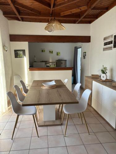 a dining room with a wooden table and white chairs at House on Rue du Phare Town Center Hosted by Christine in Quiberon