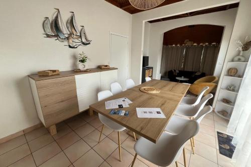 a dining room with a wooden table and white chairs at House on Rue du Phare Town Center Hosted by Christine in Quiberon