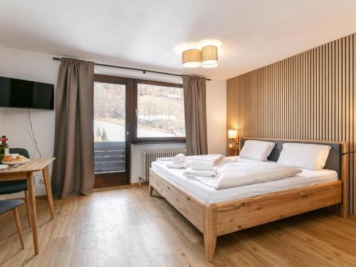 a bedroom with a bed and a table and a window at Brixen Alpin Living Top 18 in Brixen im Thale