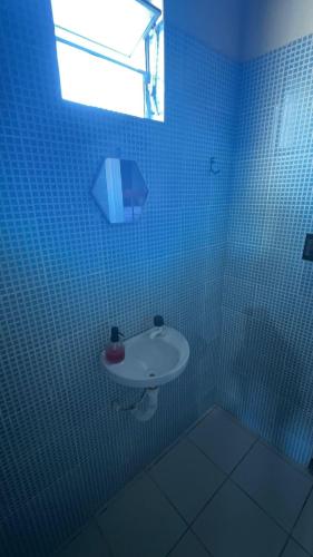a blue tiled bathroom with a sink and a window at Casas de Praia do Coqueiro com AR e varandas in Luis Correia