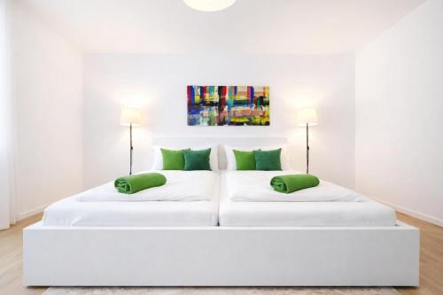 two white beds in a white room with green pillows at Nivas Collection - Neubau Luxus Apartment in Montabaur
