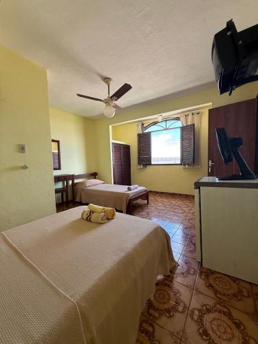 a hotel room with two beds and a ceiling fan at Pousada do Nilo in Itapemirim