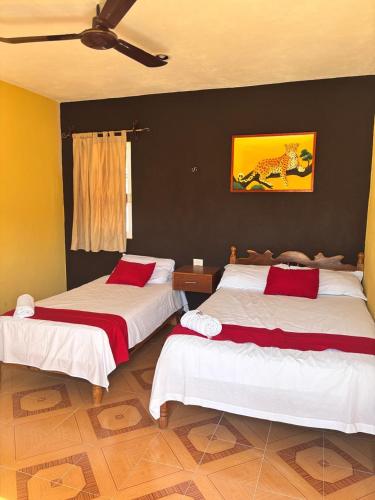 a bedroom with two beds with red and white sheets at Posada el Sol in El Cuyo
