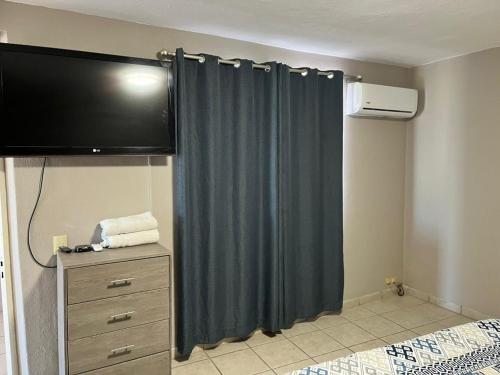 a bedroom with a curtain and a tv and a dresser at Mirador de San Miguel in San Miguel de Allende