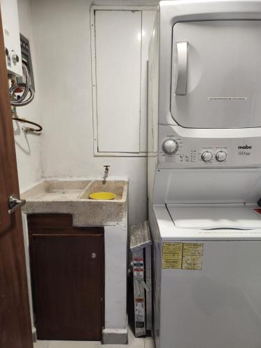 a small kitchen with a sink and a microwave at Depa nuevo en el corazón de GDL con seguridad y alberca in Guadalajara