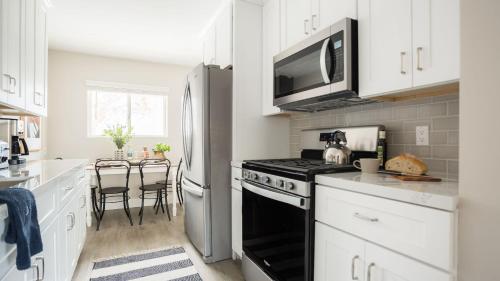 a kitchen with white cabinets and a black stove top oven at Seashore VII by AvantStay Modern La Jolla Flat 5mins from the Beach in San Diego