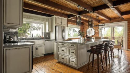 a kitchen with white cabinets and a counter with bar stools at Chateau Syrah by AvantStay Picturesque Estate w Pool Hot Tub Table Tennis Pool Table New Pickleball Court Basketball hoop in Temecula