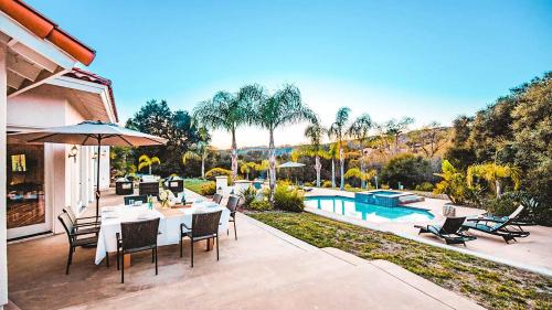a patio with a table and chairs and a pool at Grapevine by AvantStay Secluded 5BR Villa 4 Acres of Vineyards Avo Groves in Temecula
