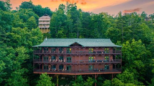 a building in the middle of a forest at Hickory Ridge by AvantStay Sleeps 20 Incredible Private Elevated Cabin in Gatlinburg