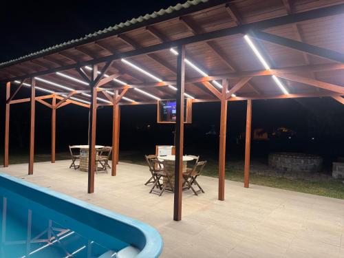 a pavilion with a table and chairs and a swimming pool at Apartamento de frente para lagoa -AP 102 in Laguna