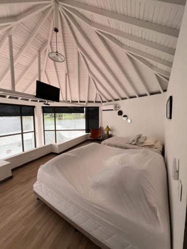 a bedroom with a large white bed in a room with windows at Afrodita Chalet in El Peñol