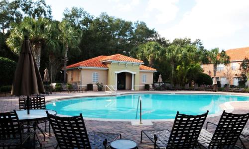 a swimming pool with chairs and an umbrella at Four Bedrooms TownHome 5161 in Kissimmee