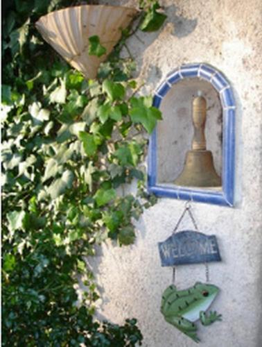 a wall with a window with a bell and a sign at L'Amandari - Chambres d'hôtes in Plan-de-la-Tour