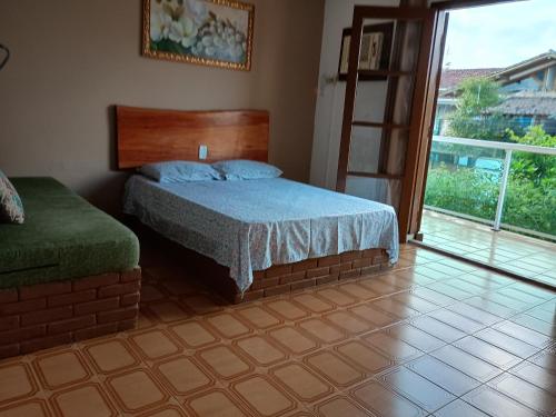 a bedroom with a bed and a large window at Casa Tapajos in Ubatuba