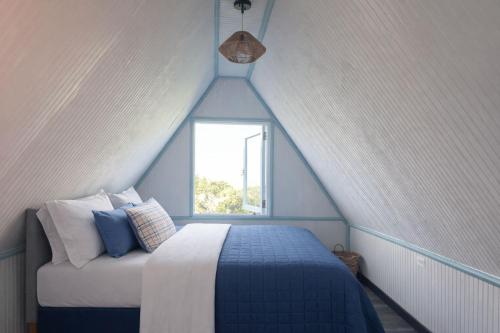 a attic bedroom with a bed and a window at Doa Blanca Cabin Mountain View in Utuado