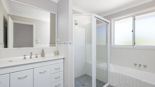 a white bathroom with a shower and a sink at Port View on the Peninsula in Lemon Tree Passage