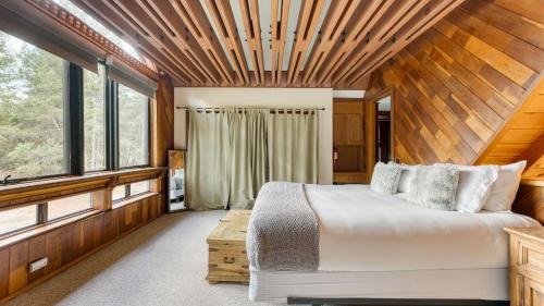 a bedroom with a large bed and some windows at Riversong Lodge by AvantStay Sauna Hot Tub On The Truckee River in Truckee