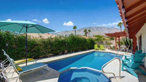 a swimming pool with an umbrella and chairs next to a house at Ranch Oasis w Private Pool HotTub Firepit Mountain Views Gobi by AvantStay in Palm Springs