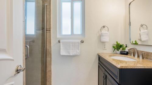 a bathroom with a sink and a shower with a window at Surfrider II by AvantStay Walk to the Beach Balcony in Newport Beach