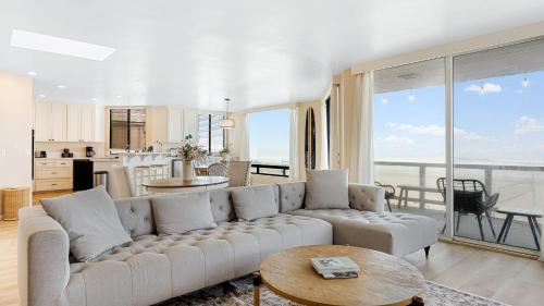 a living room with a white couch and a table at Beachfront Home w Ocean Views • Right on Mission Beach Belmont by AvantStay in San Diego