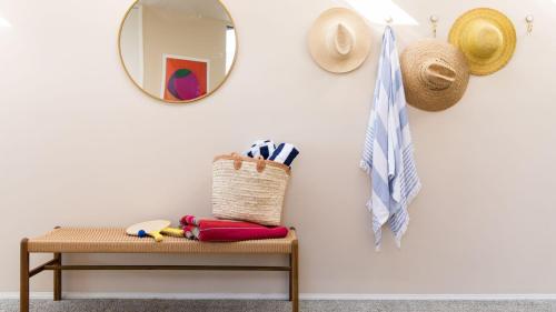 a mirror on a wall next to a bench with a hat at Beachfront Home w Ocean Views • Right on Mission Beach Belmont by AvantStay in San Diego