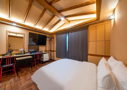 a bedroom with a white bed and a kitchen at Hotel Petit Gimpo in Gimpo