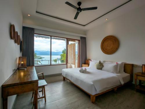 a bedroom with a bed and a desk and a window at Lay Day Gili T in Gili Trawangan