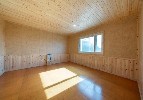an empty room with a window and a wooden ceiling at Hotel Petit Gimpo in Gimpo