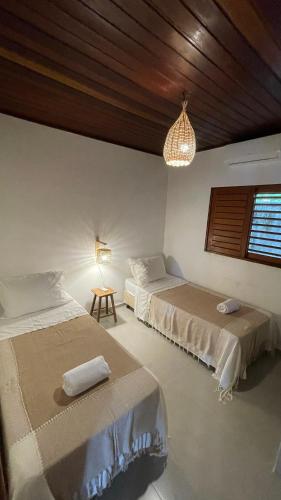 a bedroom with two beds and a chandelier at Casas Gica in Pipa