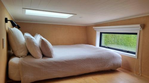 a bedroom with a bed with pillows and a window at The Tiny Diamond in Diamond Harbour