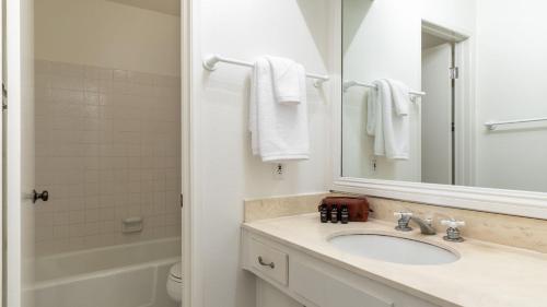 a white bathroom with a sink and a mirror at Bay View II by AvantStay Ocean View Mission Beach Home on the Sand in San Diego