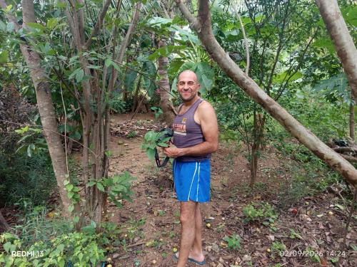 un uomo in piedi nel bosco che tiene in mano una pianta di Sun & Queen Villa a Dambulla