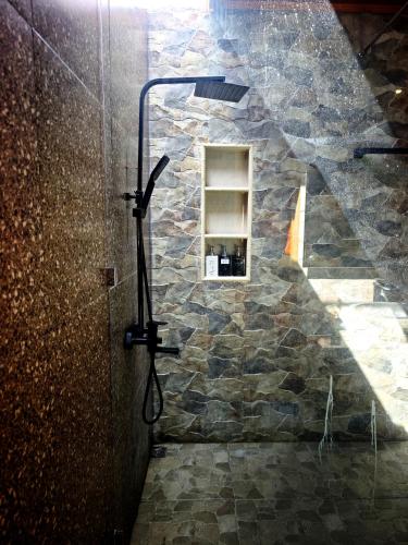 a shower in a room with a stone wall at Goroadventures and Dive Resort in Gorontalo