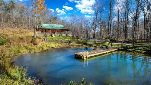 a log cabin with a pond in front of it at Charming Blue Ridge Cabin Private Pond and Waterfall Deer Haven by AvantStay in Saluda