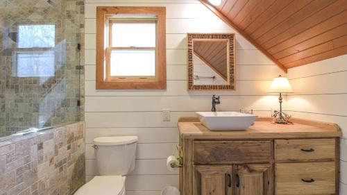a bathroom with a sink and a toilet and a mirror at Charming Blue Ridge Cabin Private Pond and Waterfall Deer Haven by AvantStay in Saluda
