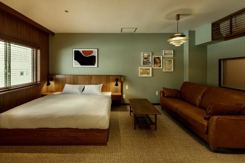 a bedroom with a bed and a couch at HOTEL&SAUNA WAYPOINT Shinano-Myoko in Shinano
