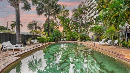 a swimming pool with chairs and palm trees at The Studio at Northshore Tower in Cairns North
